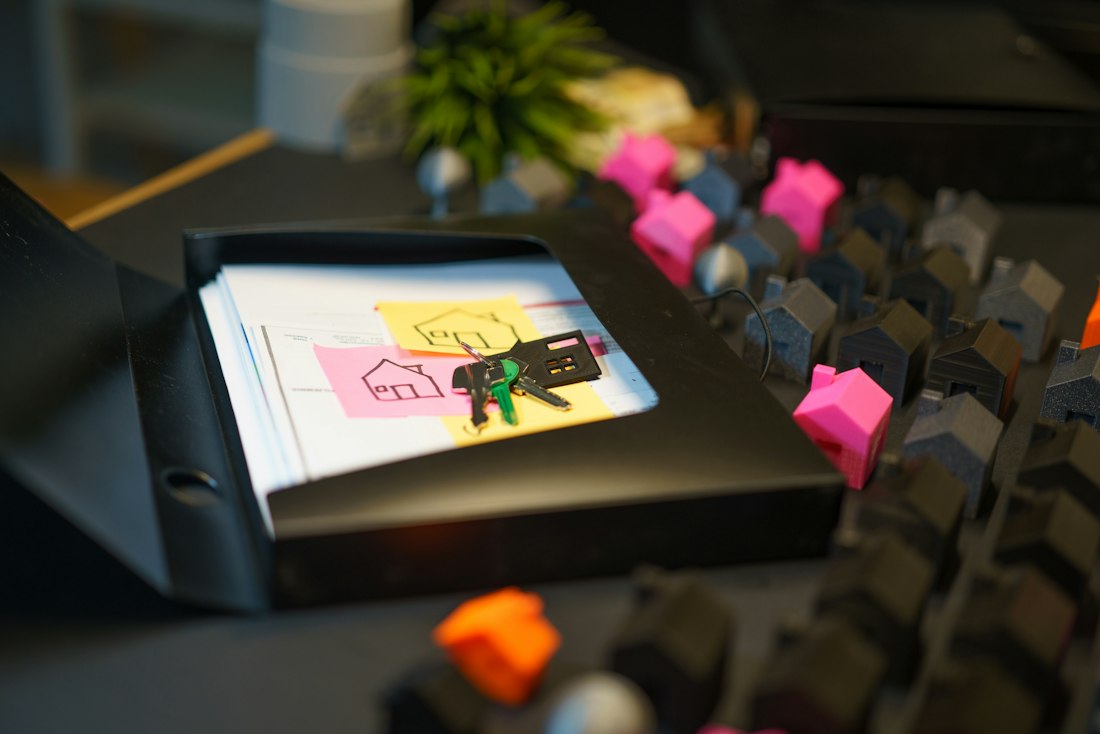 Property documents, house keys and miniature houses on a desk
