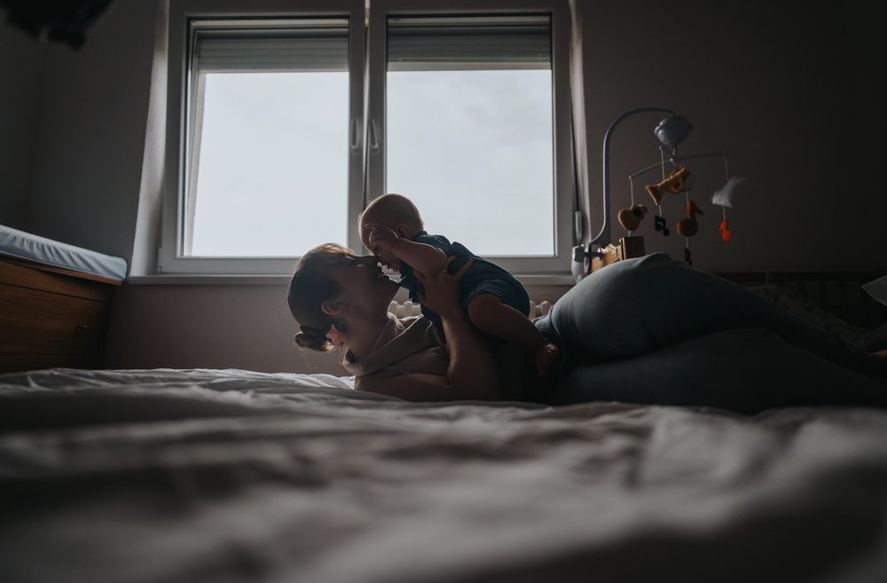 Parent holding sleeping baby near gentle window light