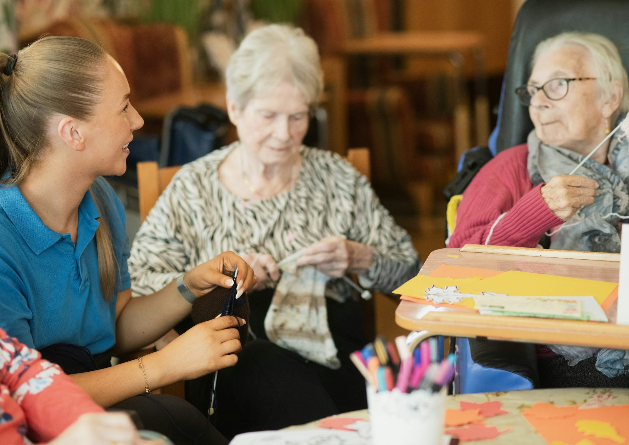 Caregiver helping senior women with a knitting activity