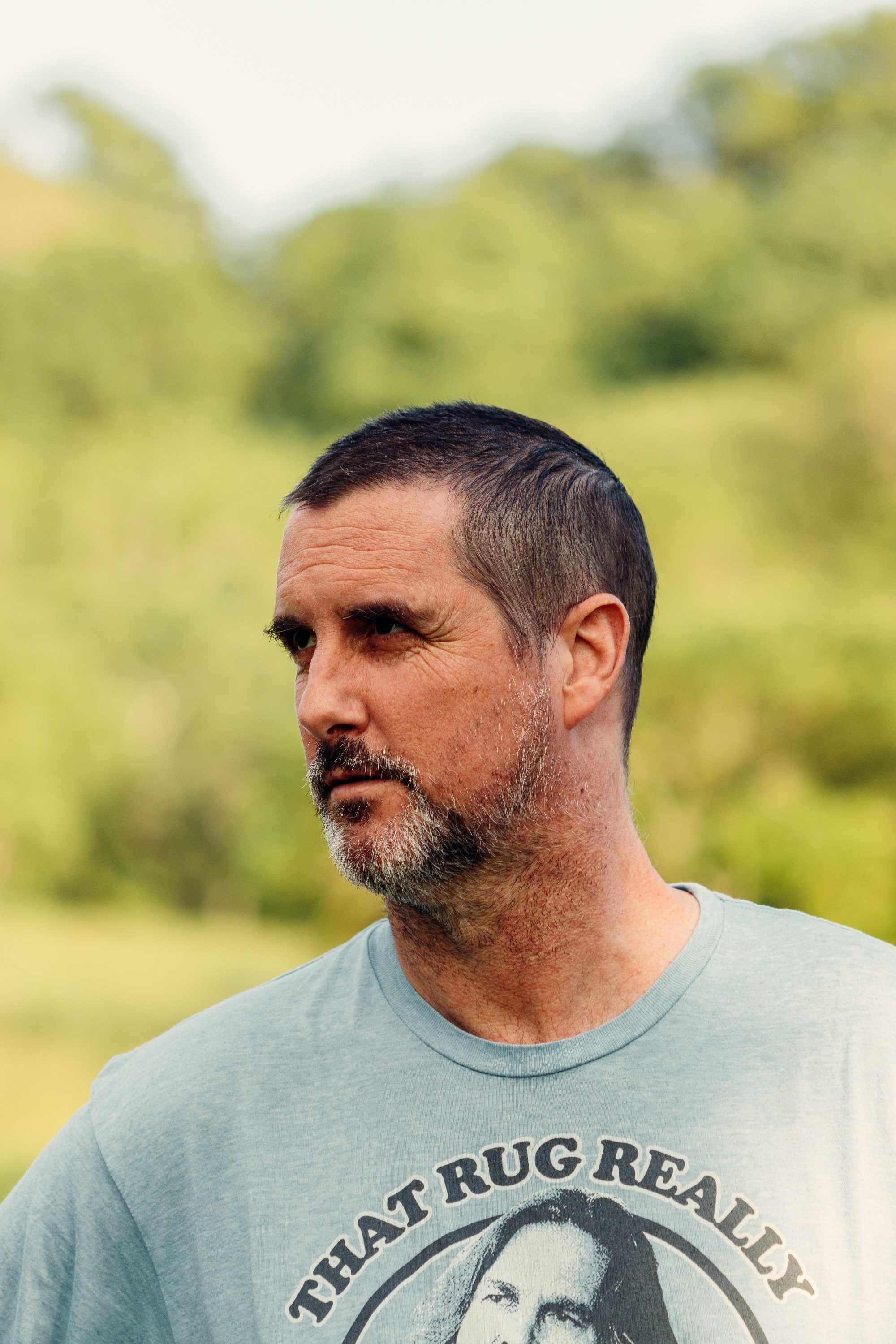 Thoughtful middle-aged man outdoors in a calm green setting