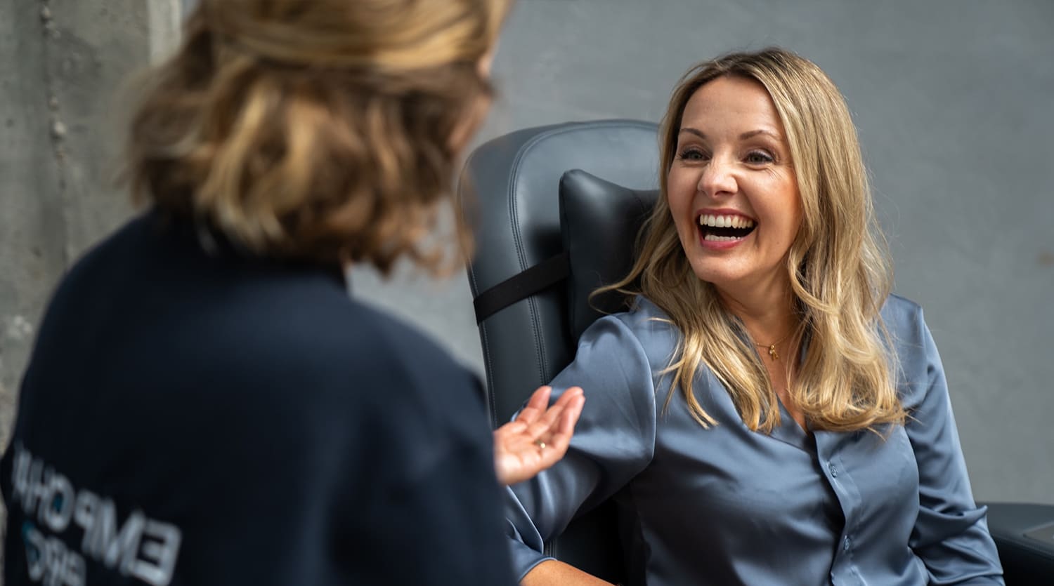 Lachende Frau im Gespräch mit einer Therapeutin, sitzend auf dem EMP Chair Pro Select