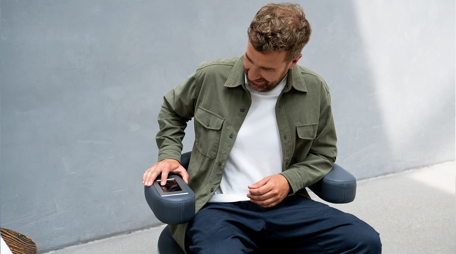 Mann sitzt in Alltagskleidung auf dem EMP Chair Pro Select und stellt das Programm am Bedienfeld ein
