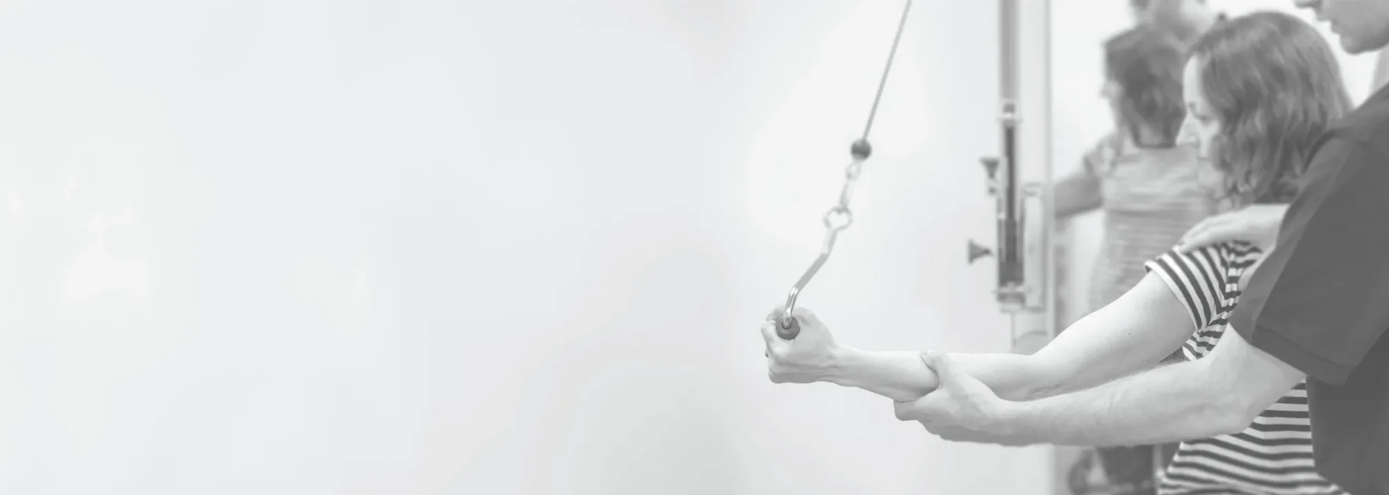 Physiotherapeut korrigiert die Armhaltung einer Patientin in den Praxisräumen von FLOW