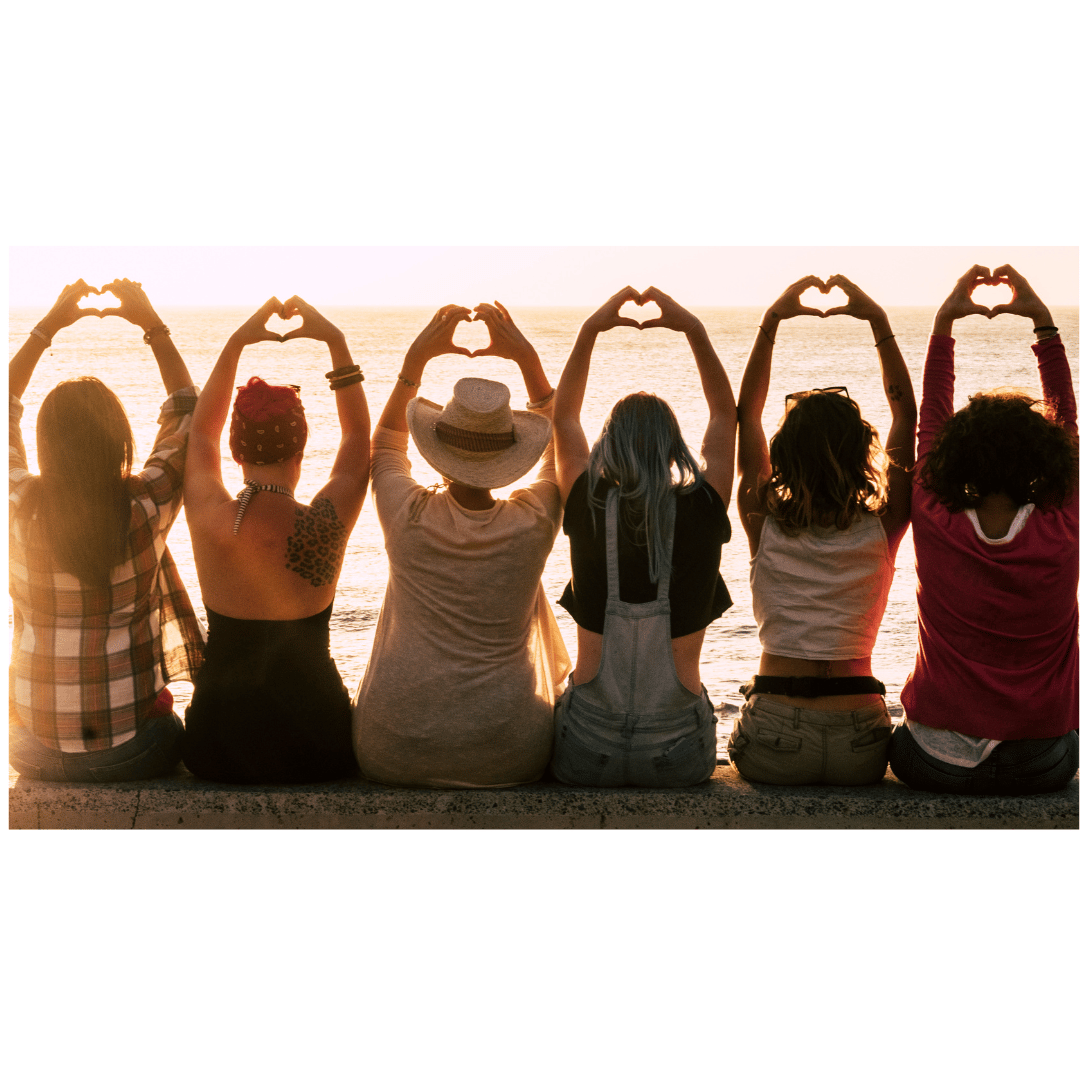 Women making heart shapes with their hands at sunset